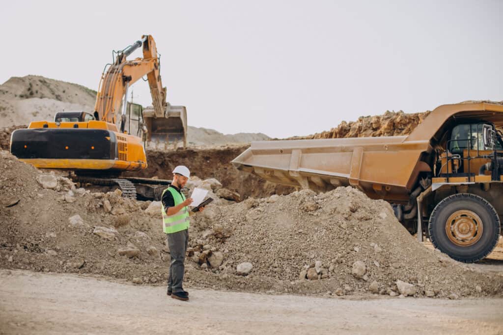 Excavator, dump truck, and worker at a construction site